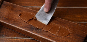 gros plan sur la spatule qui applique la pâte à bois sur la planche pour reboucher le trou
