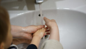 maman et enfant se lavent les mains au robinet avec de l'eau et du savon