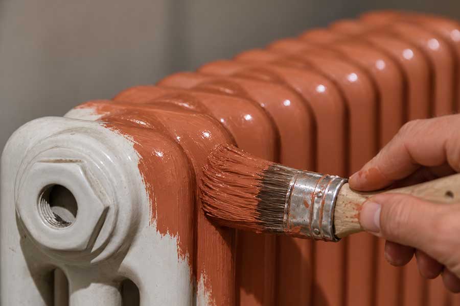 gros plan sur le pinceau qui repeint le radiateur eau chaude